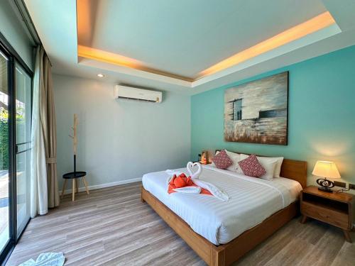 a bedroom with a large bed with blue walls at The Kiri Villas Resort in Thalang
