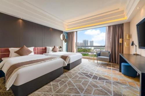 a hotel room with two beds and a television at Park Lane Hotel in Shunde