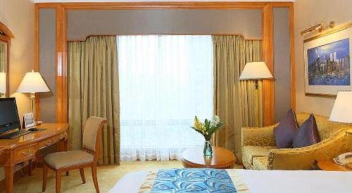 a hotel room with a bed and a desk and a window at Regency Hotel in Shantou