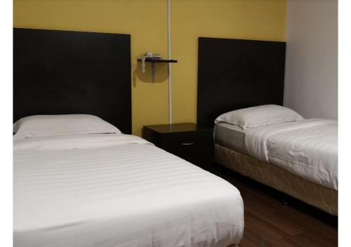 two beds in a room with two bedsskirts at Sai Villa Hotel Near Klia & Klia2 in Nilai