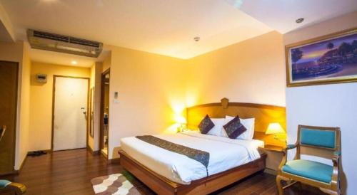 a bedroom with a large bed and a chair at NH Elegant Hotel in Sakon Nakhon