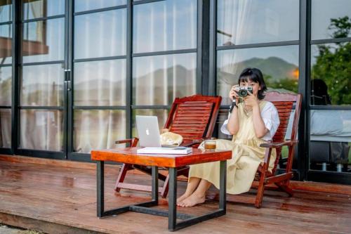 a woman sitting in a chair taking a picture with a camera at The River Life Resort in Ban Kaeng Raboet