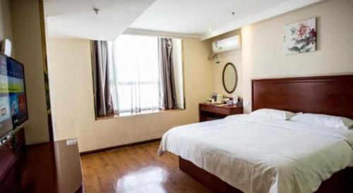 a bedroom with a large bed and a television at GreenTree Inn Luoyang Zhongzheng Street Express Hotel in Luoyang