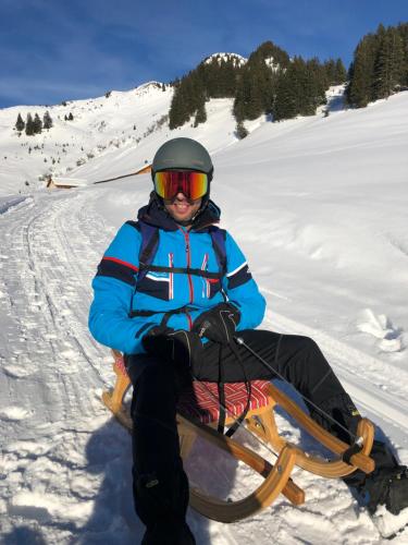 a person sitting on a sled in the snow at Ferienwohnungen Schantl in Schoppernau