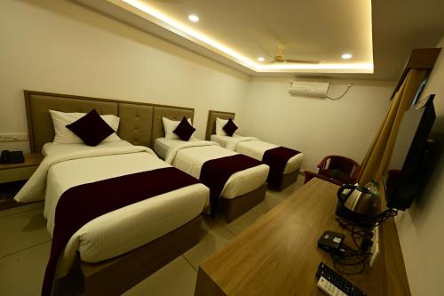 a hotel room with two beds and a television at North Fort Regency in Cochin