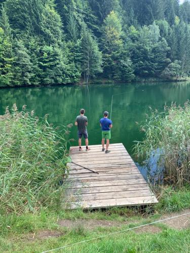 two men standing on a wooden bridge over a lake at Ferienwohnungen Schantl in Schoppernau