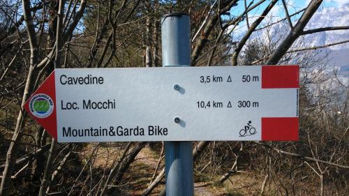 a street sign on a pole in front of trees at Appartamento Masi in Lasino