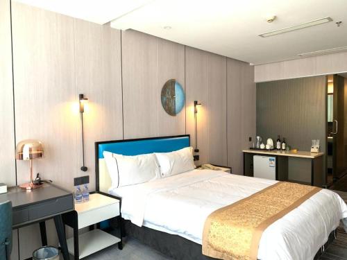 a hotel room with a large bed and a desk at Golden Central Hotel Shenzhen in Shenzhen