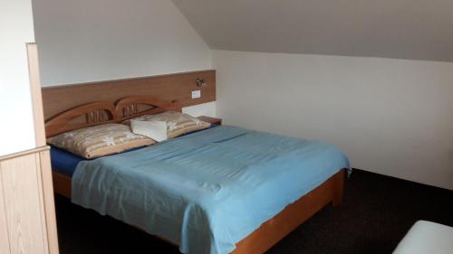 a bedroom with a bed with blue sheets and pillows at Penzión Marco Polo in Vrútky