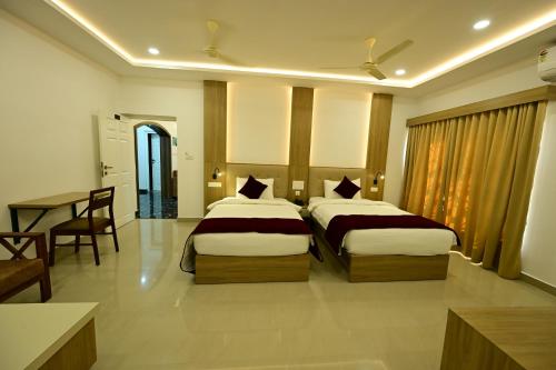 a hotel room with two beds and a table at North Fort Regency in Cochin
