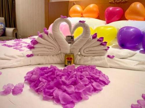two swans made out of towels on a bed with flowers at Vienna Hotel Shenzhen Bao'an Airport Taoyuanju Pingluanshan Metro Station in Shenzhen
