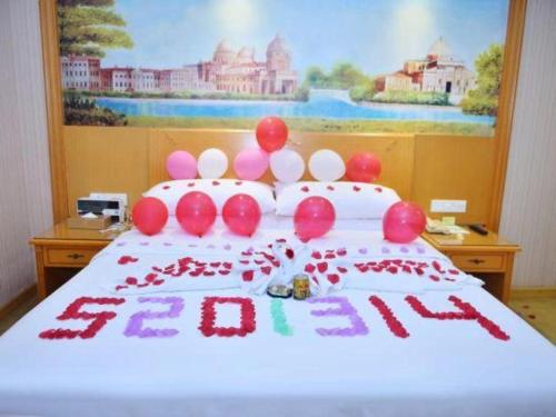 a bed with a birthday cake with balloons on it at Vienna Hotel Shenzhen Bao'an Airport Taoyuanju Pingluanshan Metro Station in Shenzhen