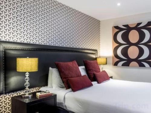 a bedroom with a large white bed with red pillows at Oaks Queenstown Club Suites in Queenstown