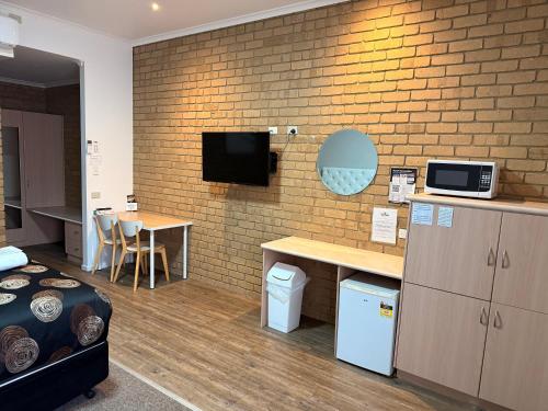 a room with a bed and a tv on a brick wall at Tropicana Motor Inn in Cowes