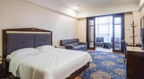 a hotel room with a large bed and a living room at Zhongshan Hui Quan Hotel in Zhongshan