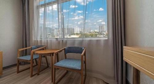 a room with two chairs and a table and a window at GreenTree Inn Haixi Geermu Southern suburbs Express Hotel in Golmud