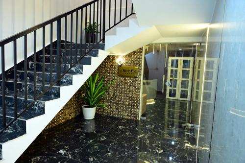 a hallway with a staircase with black marble floors and a stair case at North Fort Regency in Cochin