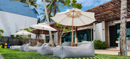 a row of chairs with umbrellas on a lawn at Simada Resort&Cafe - สิมาดา สิชล in Ban Plai Thon