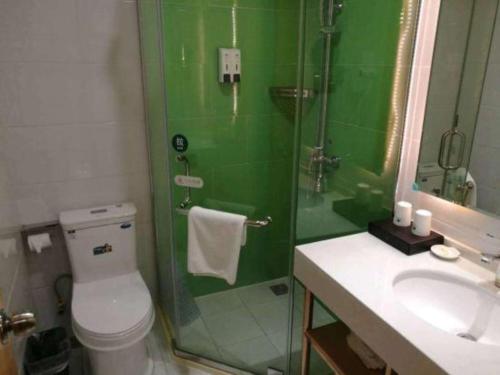 a green bathroom with a toilet and a shower at GreenTree Inn Yancheng Yandu District Hongxing Macalline Century Avenue in Yancheng