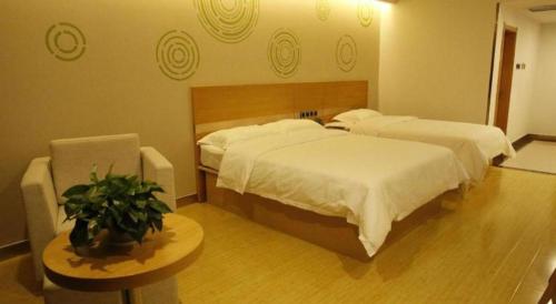 a bedroom with two beds and a table with a plant at GreenTree Inn Ordos Kangbashi District Ulan Mulun Street Branch in Ordos