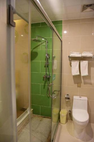 a bathroom with a shower and a toilet and green tiles at GreenTree Inn Qinhuangdao Changli County Guangyuan Life Square Duanyang Street East Section in Qinhuangdao
