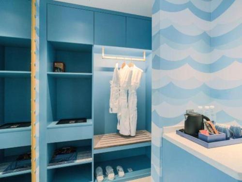 a blue walk in closet with white clothes and shoes at Dolphin Bay Hotel in Yanglin