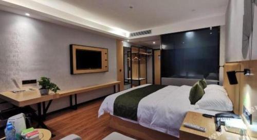 a bedroom with a bed and a desk and a tv at GreenTree Inn Ganzhou Gan County Bus Station in Ganzhou
