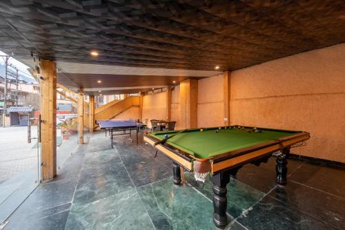 a pool table in a room with two tables at Hill Rive Resort in Manāli