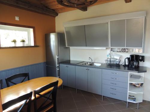 a kitchen with a table and a stainless steel refrigerator at Hjärtasjöstugor in Lönsboda
