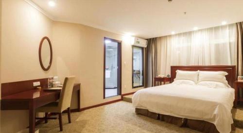 a hotel room with a bed and a desk and a desk at GreenTree Inn Puyang Pushang Huanghe Road in Puyang
