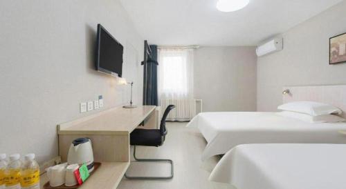 a hotel room with two beds and a desk with a television at Jinjiang Inn Dalian Development Zone Jinma Road Light Railway Station in Jinzhou