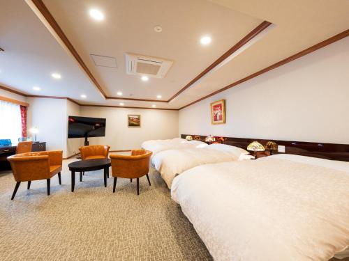 a hotel room with three beds and a flat screen tv at BeppuOnsen Hotel Sansenkaku in Beppu