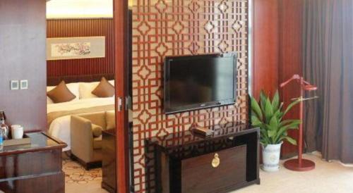 a living room with a television on a wall at Zhangjiagang Zhonglian GDH International Hotel in Zhangjiagang