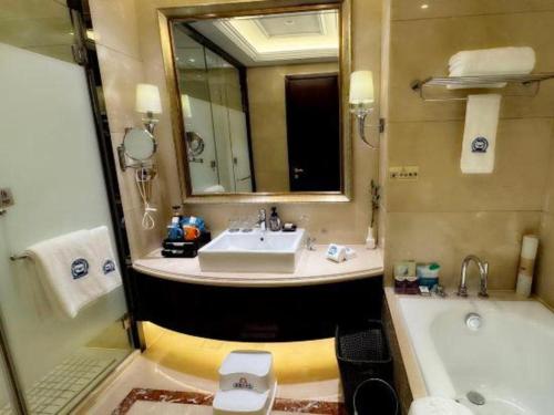 a bathroom with a sink and a tub and a toilet at Linyi Blue Horizon International Hotel Yi He in Linyi
