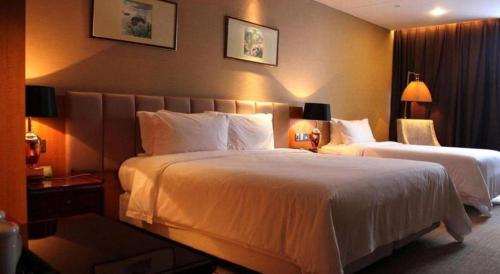 a hotel room with two beds and two lamps at Zhangjiagang Zhonglian GDH International Hotel in Zhangjiagang