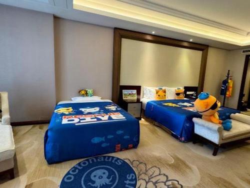 a bedroom with two beds and a stuffed animal sitting on a chair at Linyi Blue Horizon International Hotel Yi He in Linyi