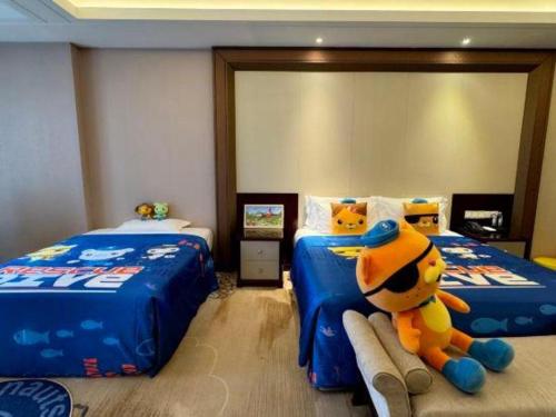a bedroom with two beds with a stuffed animal sitting between them at Linyi Blue Horizon International Hotel Yi He in Linyi