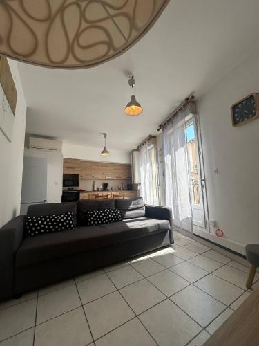 un salon avec un canapé noir dans une pièce dans l'établissement Le Marceau, à Mèze