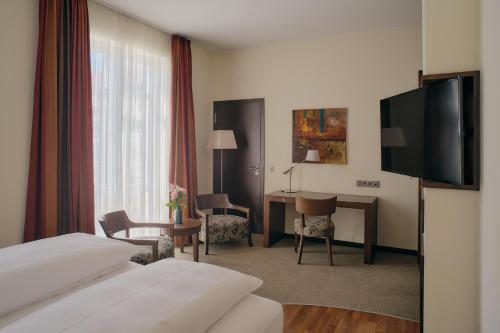 a hotel room with a bed and a desk and a television at Aparthotel Treudelberg Hamburg in Hamburg