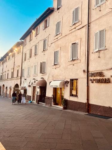 a building on a street with people walking in front of it at Hotel Roma Assisi in Assisi