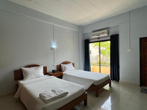 two beds in a room with a window at Ritzy House Hotel in Chumphon