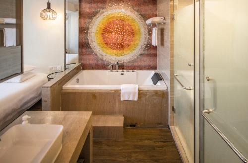 a bathroom with a tub and a sink and a mirror at Xiamen Gulangyu Heitan Hotel in Xiamen