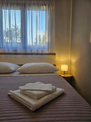a bed with two towels on it with a window at Apartmani Mariva in Dicmo