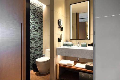 a bathroom with a sink and a toilet and a mirror at Fairfield by Marriott Yantai in Yantai