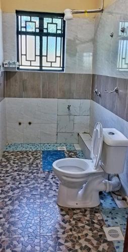 a bathroom with a toilet and a tiled floor at Elboran resort and spa in Isiolo