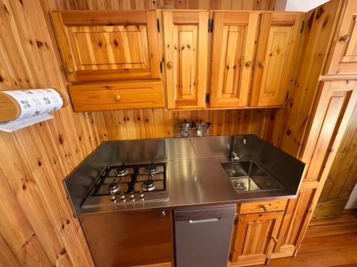 a kitchen with a stove top and wooden cabinets at Casa Gatto in Auronzo di Cadore