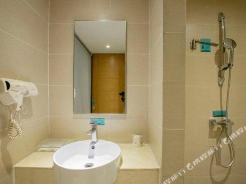 a bathroom with a sink and a shower with a mirror at City Comfort Inn Nanning Zoo Keyuan Avenue in Nanning