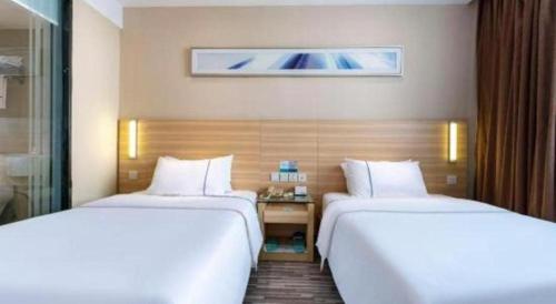 a hotel room with two beds and a desk at City Comfort Inn Foshan Shunde Daliang Qinghui Garden Xinsong in Shunde