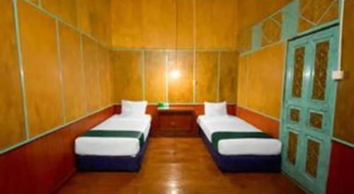 two beds in a small room with wooden walls at Bunda House Syariah in Padang