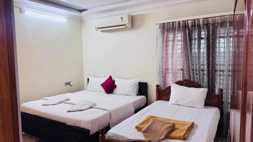 two beds in a room with white walls at Fortune Homestay Tirupati in Tirupati